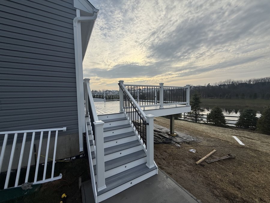 Elevated composite deck with a wide staircase overlooking a lake, built by E.B.R Deck Builder