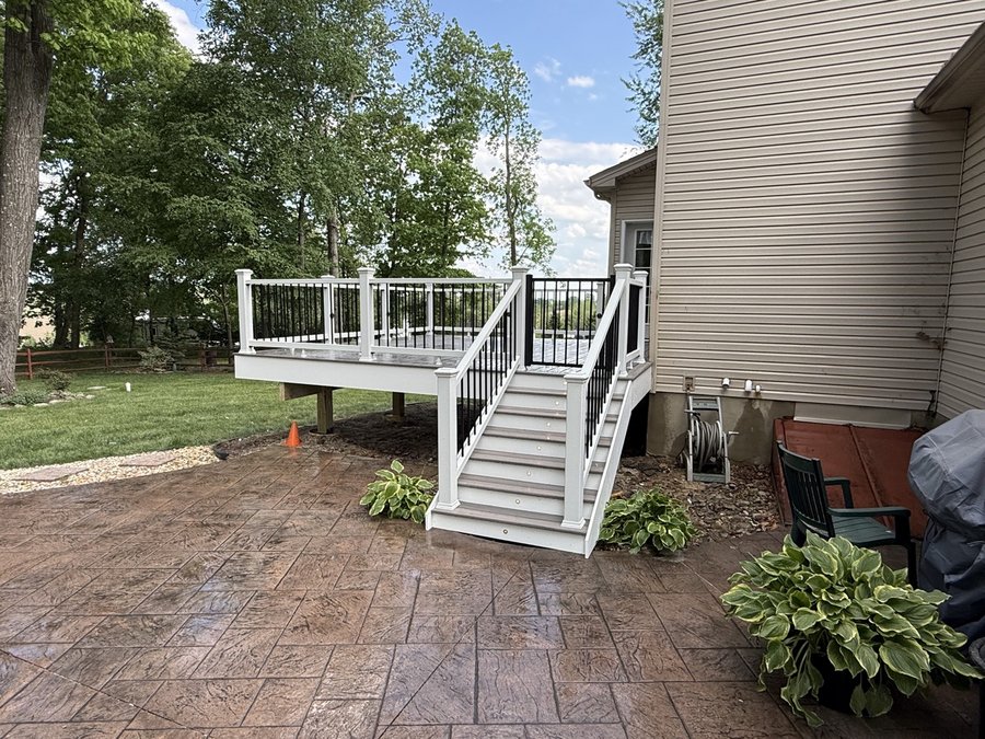 Tall composite deck with a long staircase down to a stamped-concrete patio