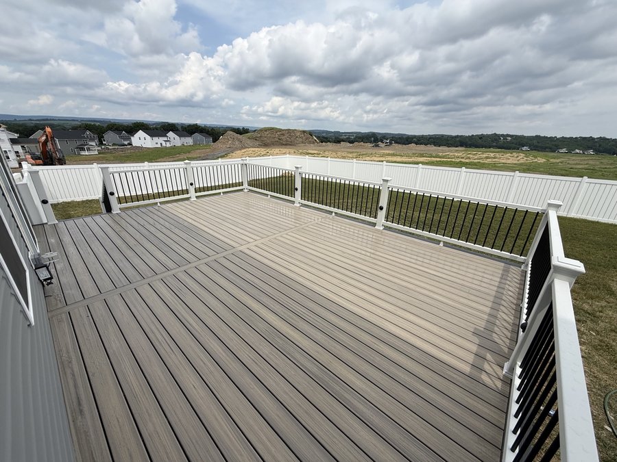 Extra-wide gray composite deck with white and black railings overlooking open land