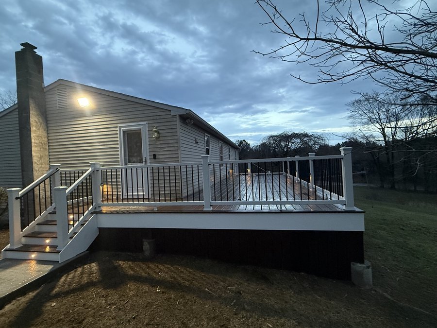 Raised composite deck at dusk with lights glowing on the staircase steps