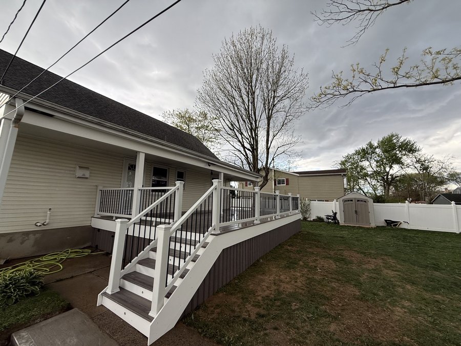 Full-length composite deck running along a house, with a wide staircase to the yard