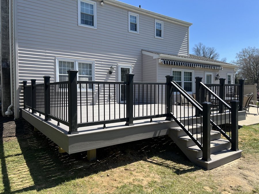 Gray composite deck with black aluminum railing on a two-story house