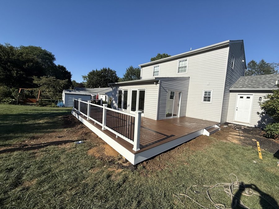 Long two-tone composite deck running along a white house with white and black railings