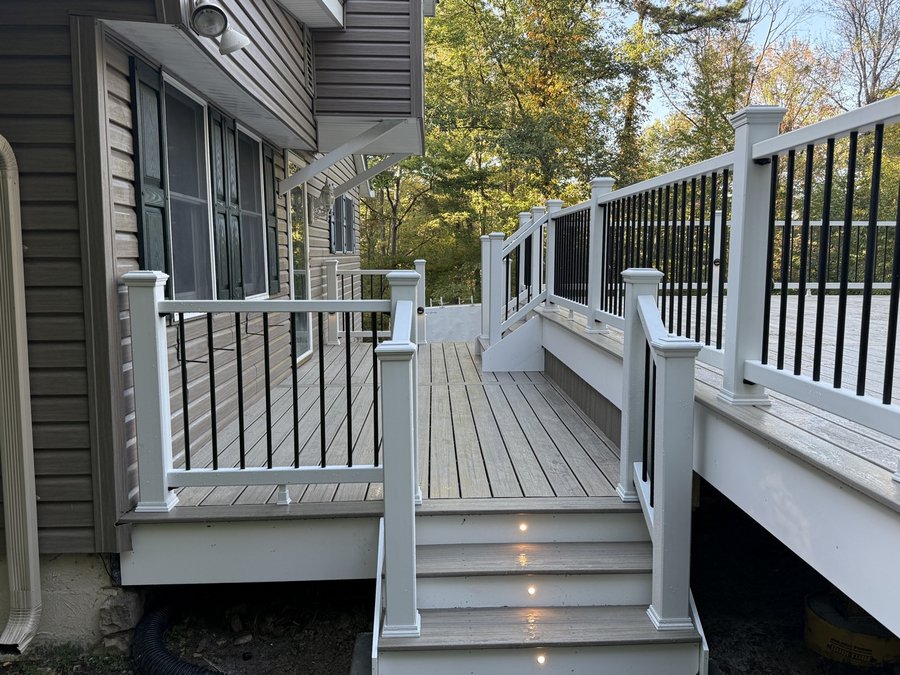 Composite deck and staircase with white posts and black balusters in the evening